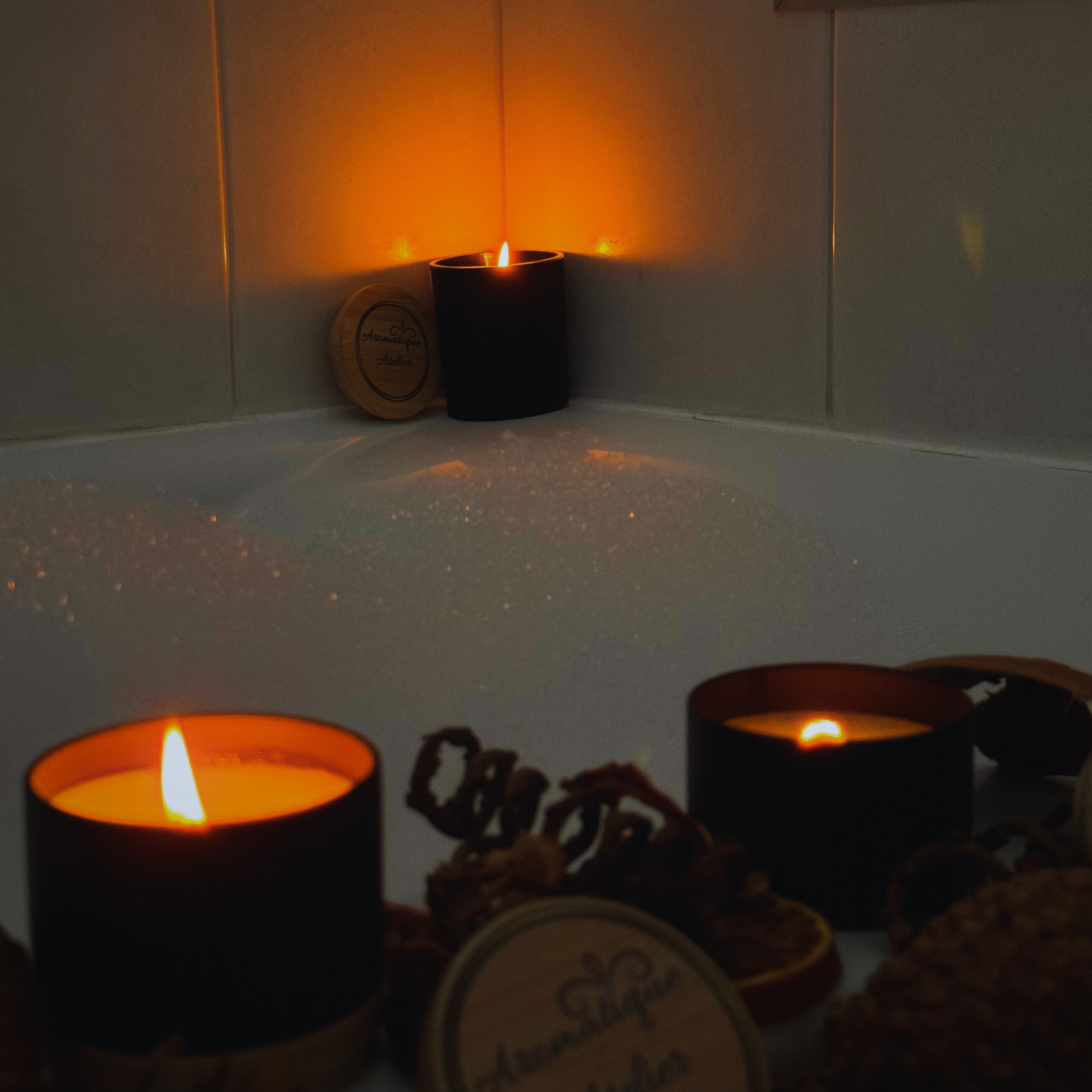 47+H Premium Candle - The One Inspired, two burning candles creating a warm ambiance in a bathroom setting.